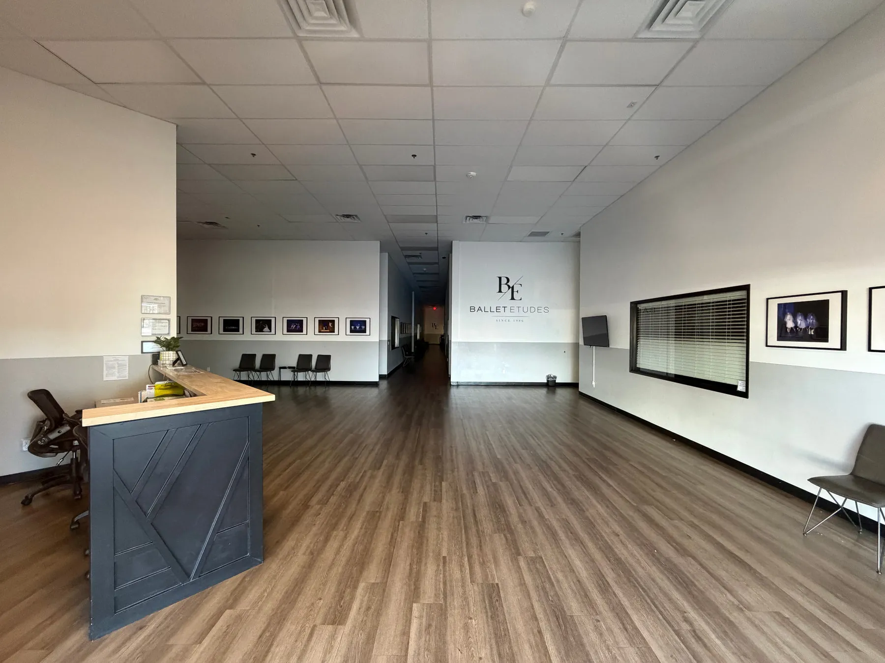 Ballet Etudes lobby with wood-look flooring, reception desk, and framed photos on white walls