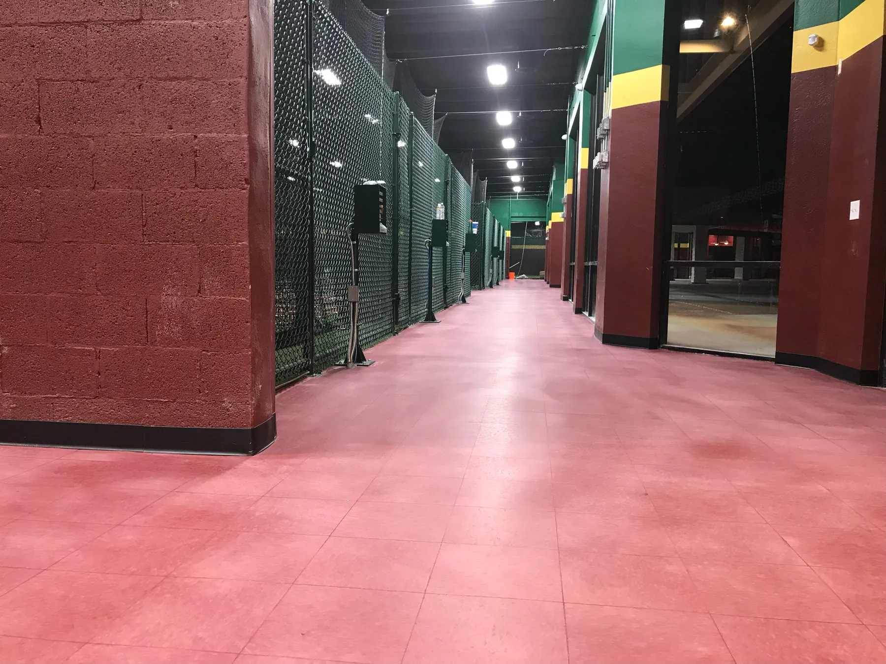 D-Bat batting cage facility with red floor and netted cage lanes